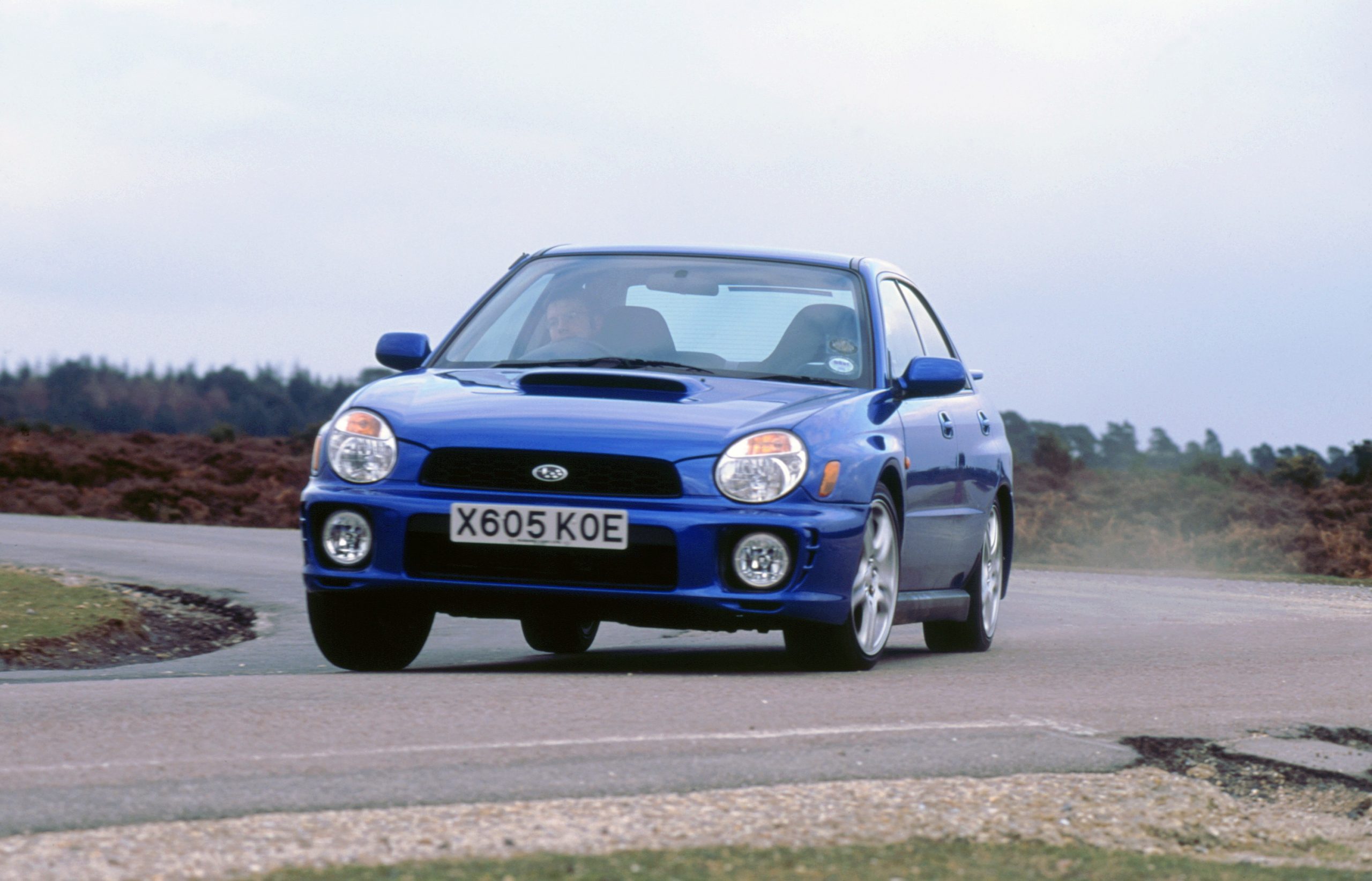 A blue Subaru WRX cornering at full speed, shot from the 3/4 angle