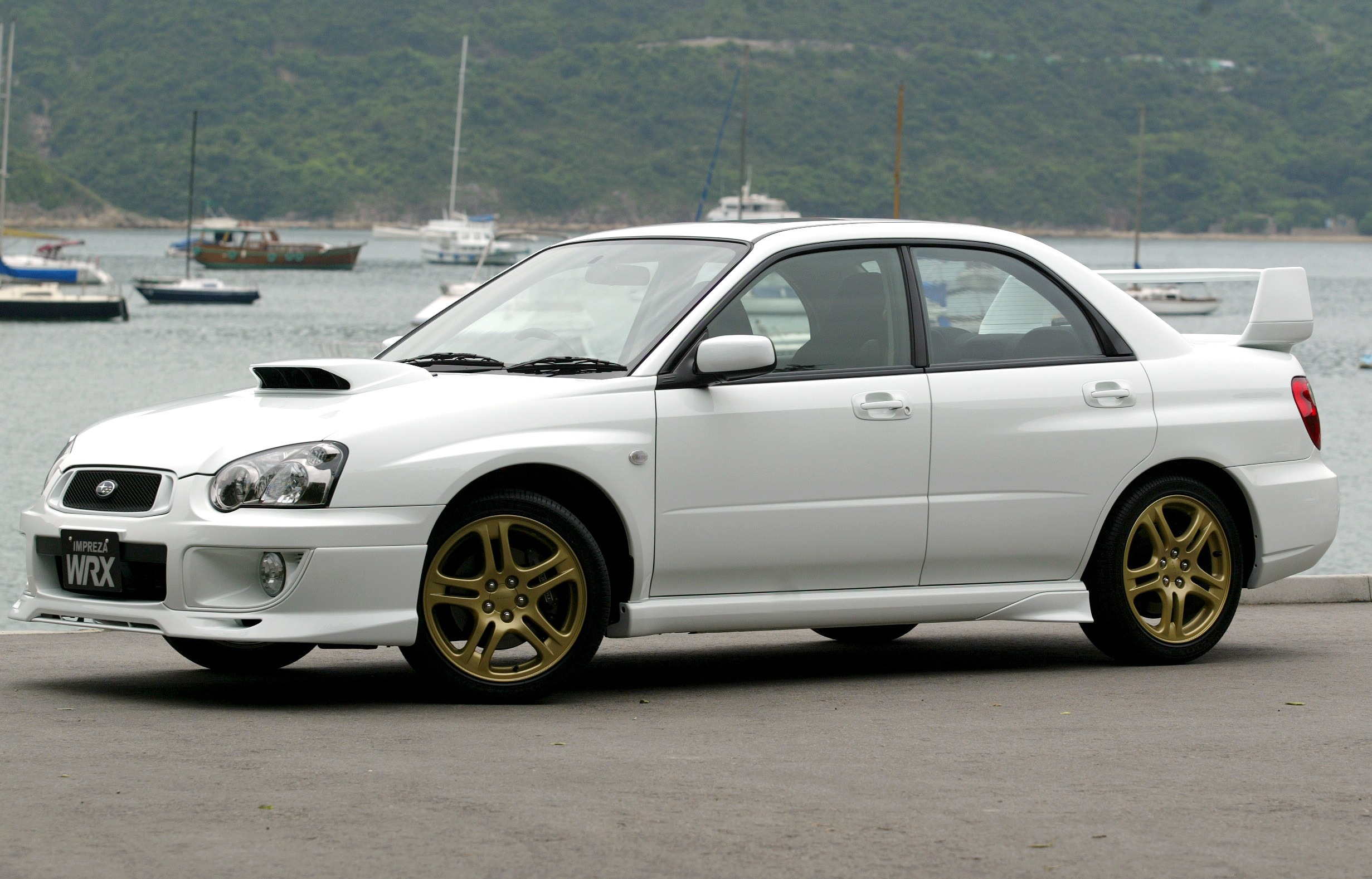 A white Subaru WRX STI shot from the front 3/4 angle in a harbor