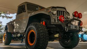 A low-angle front 3/4 view of a gray 1955 Willys-Overland Jeep Truck at the 2021 Mecum Chicago auction