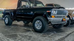 The front 3/4 view of a black restored 1981 Jeep J10 at the 2021 Mecum auction in Chicago