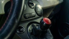 A red-and-black CravenSpeed short shifter in a 2013 Fiat 500 Abarth