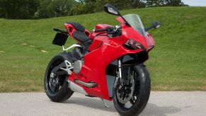 A red 2014 Ducati 899 Panigale motorcycle next to a grassy field