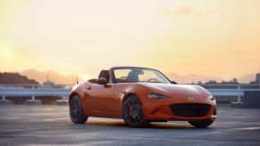 A orange 2019 Mazda MX-5 Miata on a blacktop area with an orange sky in the background