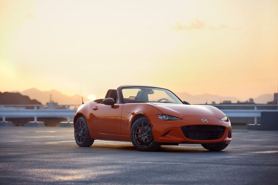 A orange 2019 Mazda MX-5 Miata on a blacktop area with an orange sky in the background