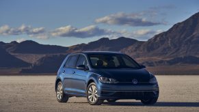 A dark turquoise blue 2021 Volkswagen Golf hatchback shot from the front 3/4 on a lake bed