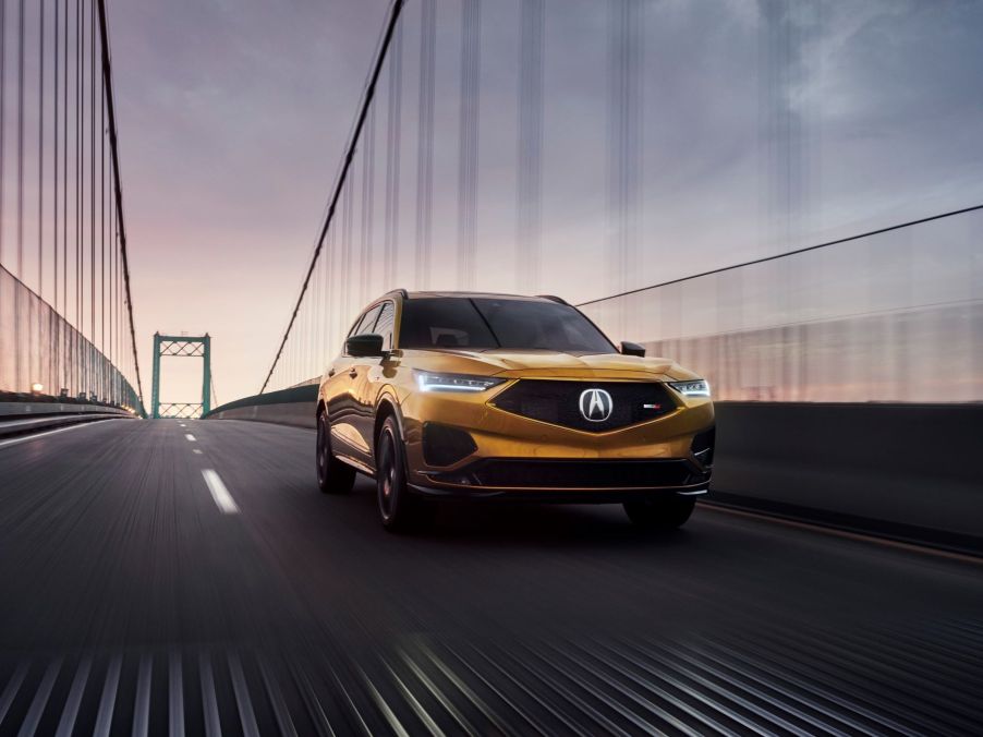 The 2022 Acura MDX Type S three-row midsize SUV with a burnt orange/bronze paint color option driving over a bridge