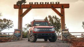 A red 2022 Ford Bronco parked near a large wooden Bronco sign, is the Wildtrak trim worth the price tag?