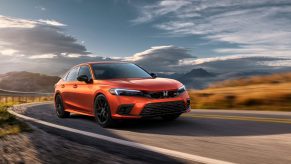 An orange Honda Civic Si shot on a back road from the 3/4 angle