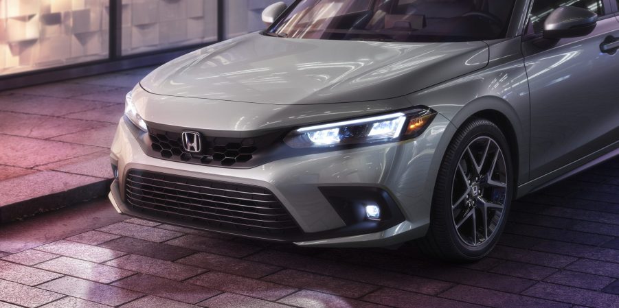 A white 2022 Honda Civic sedan shot at night on a city street from the nose forward