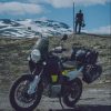 A black-silver-and-green 2022 Husqvarna Norden 901 with accessory bags parked on an alpine country road