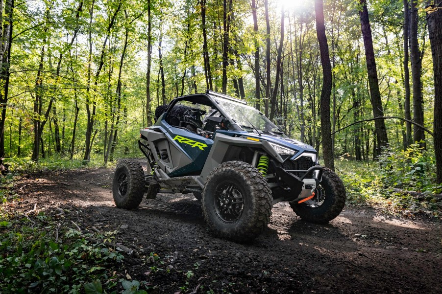 A green-and-gray 2022 Polaris RZR Turbo R Premium in the forest