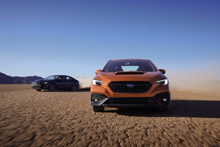 An orange 2022 Subaru WRX shot from the front on a dry lake bed with a blue model close behind