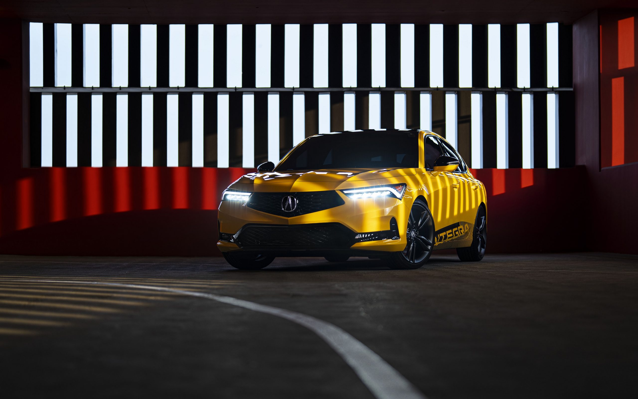 A Phoenix Yellow 2023 Acura Integra, shot from the front 3/4 angle in a parking garage