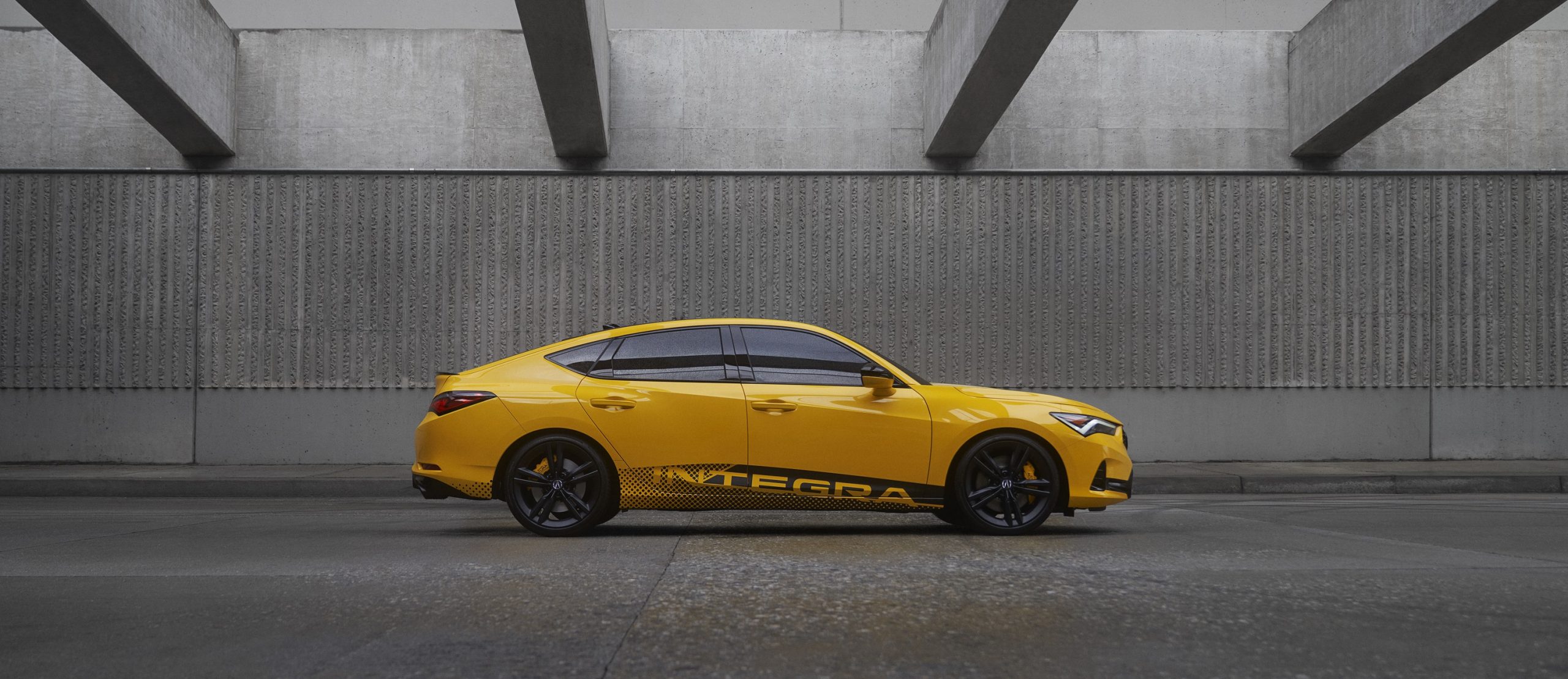 A yellow Acura integra shot in profile inside a parking garage