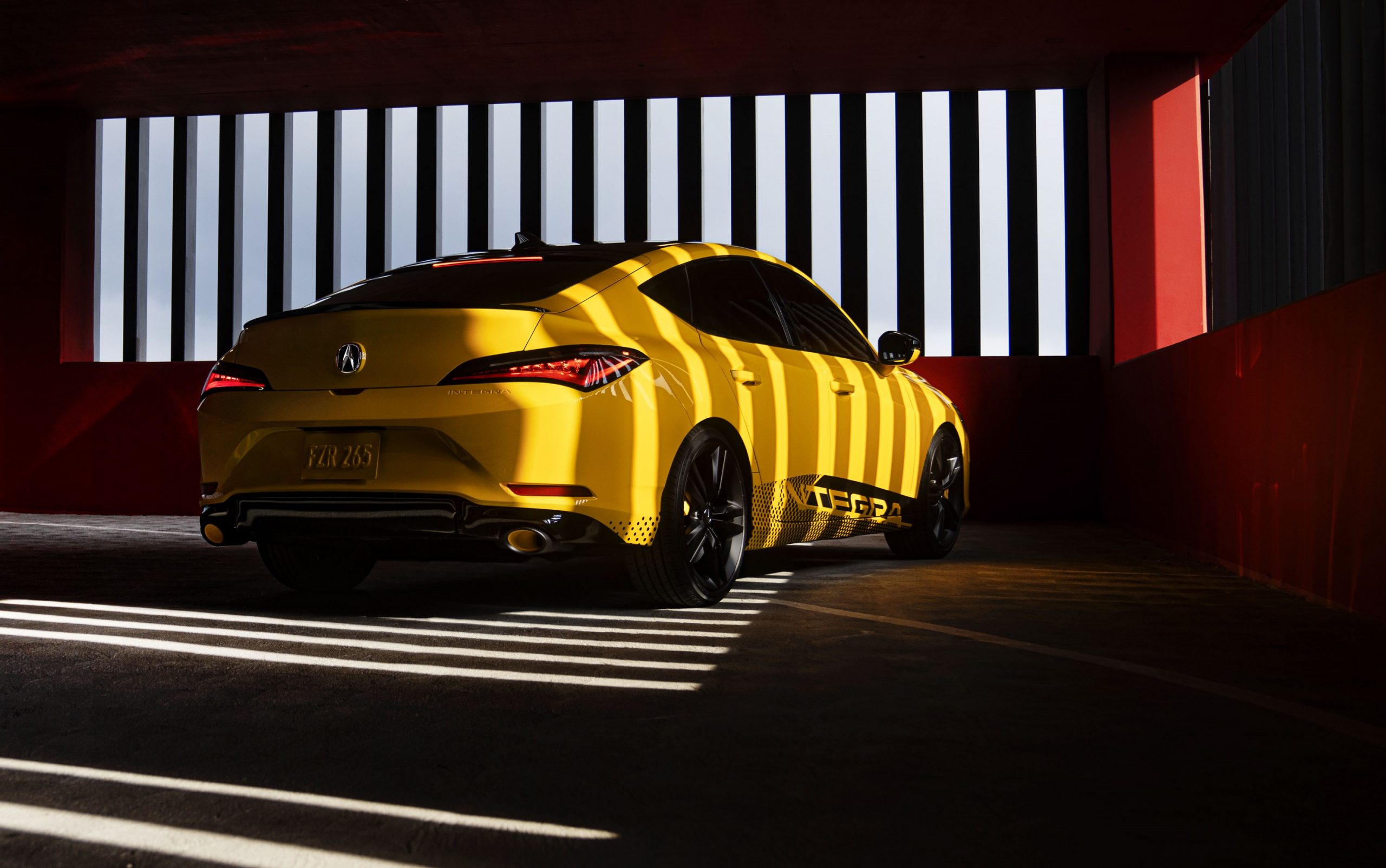 A yellow Integra, shot from the rear 3/4 in a parking garage