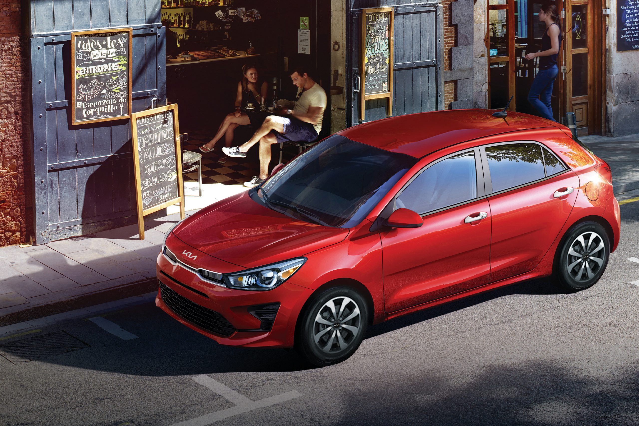 A red 2022 Kia Rio hatchback shot from the high 3/4 on a city side street