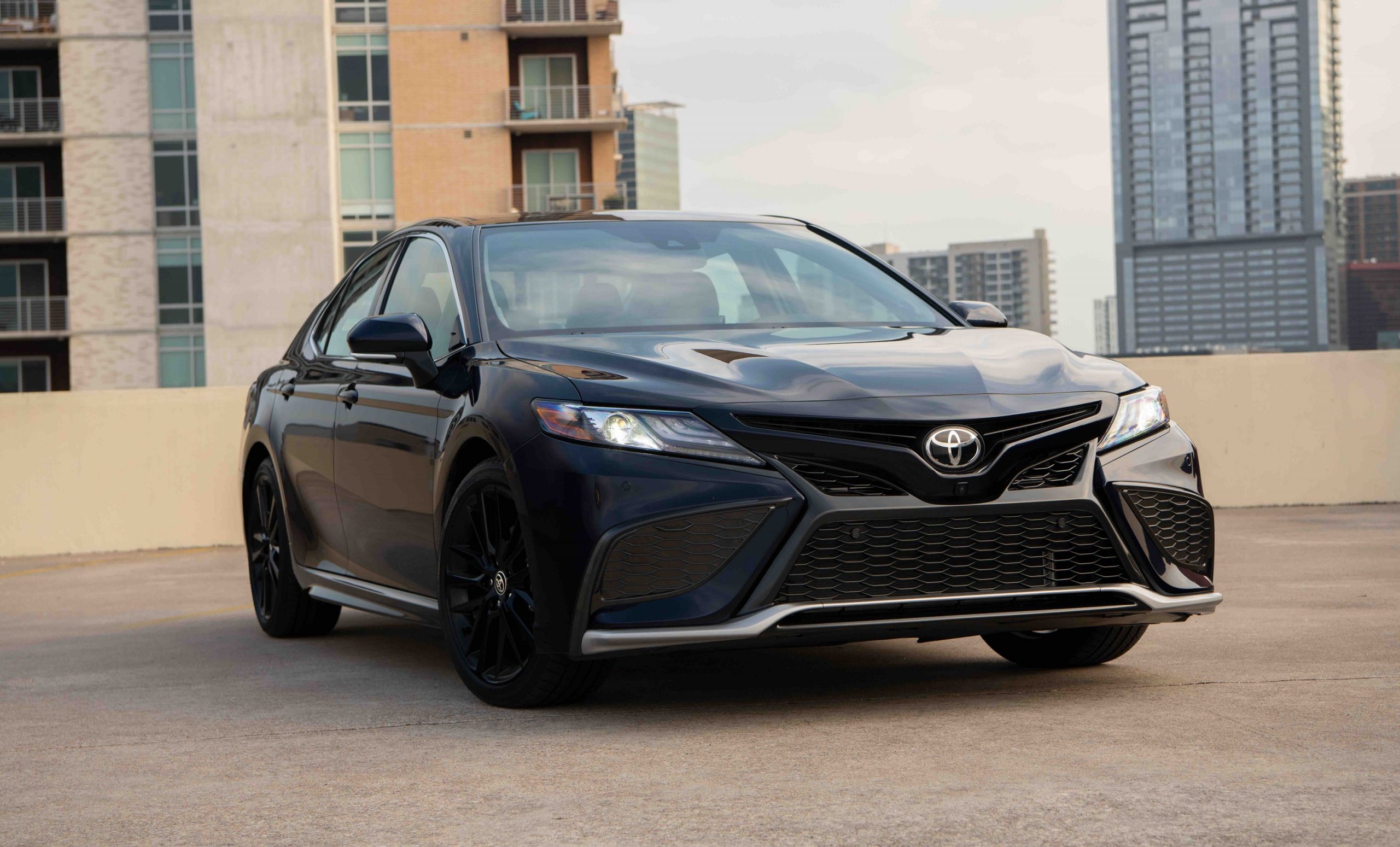 A black Toyota Camry shot from the front 3/4 at sunset