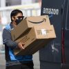 An Amazon.com Inc. delivery driver carries boxes into a van outside of a distribution facility. Employees like this were who Amazon was stealing tips from.