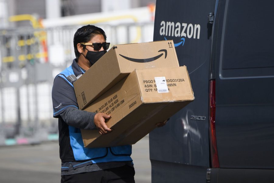 An Amazon.com Inc. delivery driver carries boxes into a van outside of a distribution facility. Employees like this were who Amazon was stealing tips from.