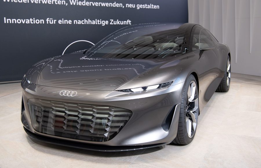 A silver Audi Grandsphere on a white slab inside of a grey building.