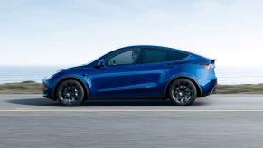 Blue 2022 Tesla Model Y electric crossover driving on a coastal road