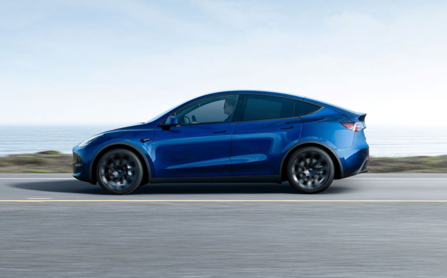 Blue 2022 Tesla Model Y electric crossover driving on a coastal road