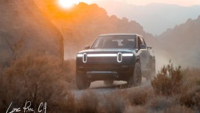 Blue Rivian R1T driving by a large rock