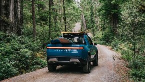 Blue Rivian R1T driving through a forest