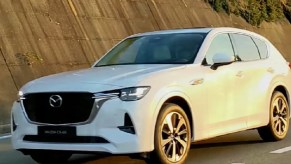 A white 2022 Mazda CX-60 driving down a road.