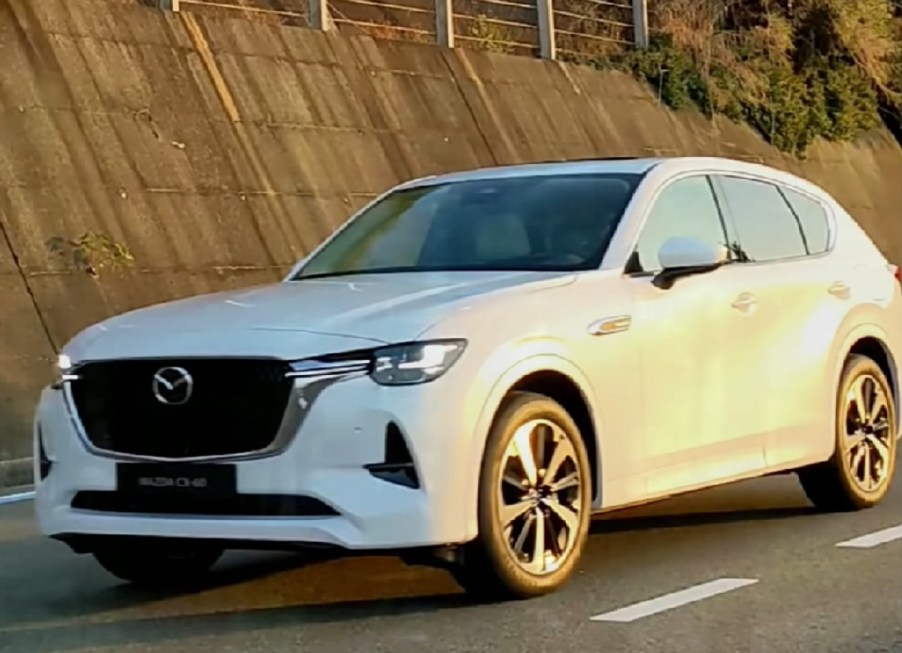 A white 2022 Mazda CX-60 driving down a road.