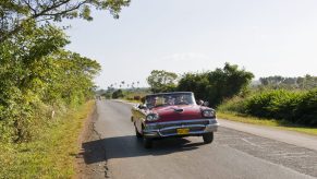 1958 Ford Fairlane, a beautiful classic car, driving down the road with the top down.