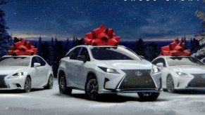 A white Lexus SUV and cars with red Christmas bows on top.