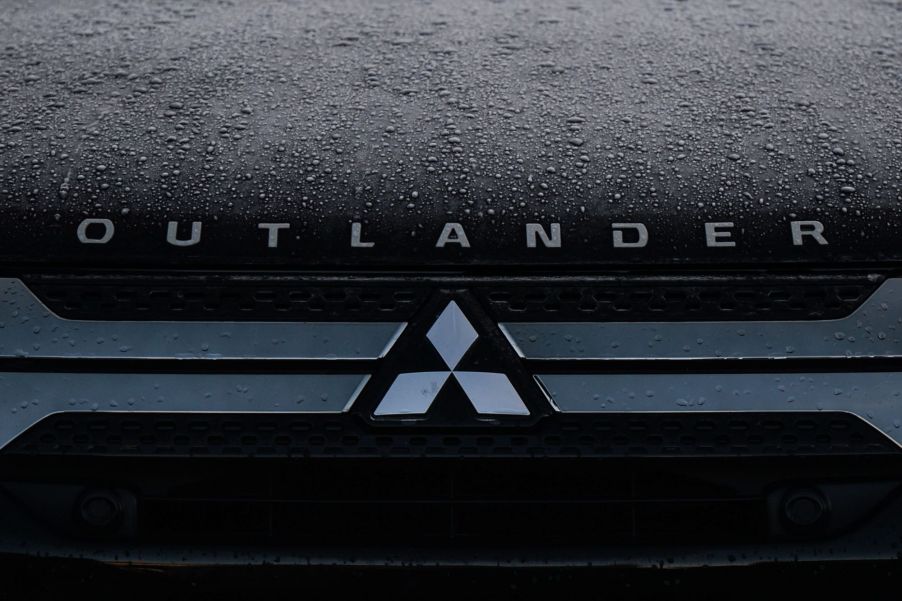 A Mitsubishi Outlander logo on a black background with raindrops.