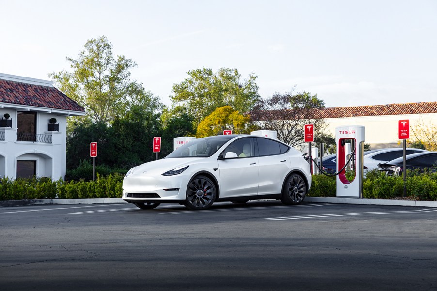 A white Tesla Model Y at a Tesla Supercharger