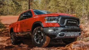 Orange-red 2022 Ram 1500 driving up a pile of rocks