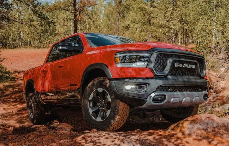 Orange-red 2022 Ram 1500 driving up a pile of rocks