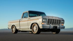 Passenger's side front angle view of grey and orange Ford F-100 EV pickup truck at SEMA 2021