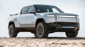 Passenger's side front angle view of silver Rivian R1T in a comparison between the Rivian R1S