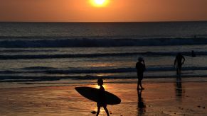 People on Kuta Beach in Bali, Indonesia as the sun sets over the ocean