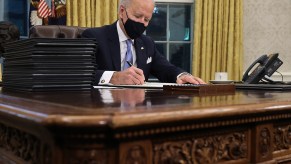 President Joe biding in the oval office signing a bill