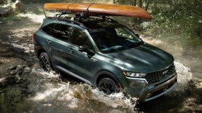 A dark green 2022 Kia Sorento splashing across a river.