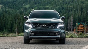 A dark colored 2022 Kia Sorento in front of a log cabin.