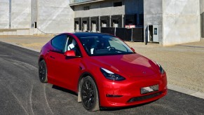 A red Tesla Model Y is parked outside a building.