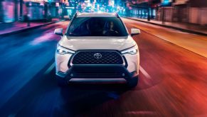 White 2022 Toyota Corolla Cross driving on a city street at night