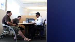 car salesperson sits at desk and goes over lease terms with a customer