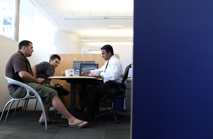 car salesperson sits at desk and goes over lease terms with a customer