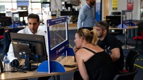 A car salesman talks to a customer from behind a screen