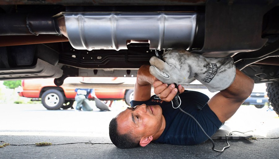 Technician engraving a catalytic converter to prevent catalytic converter theft