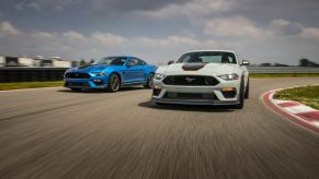 A pair of Ford Mustang Mach 1's in fighter grey and blue shot on a race track from the 3/4 angle