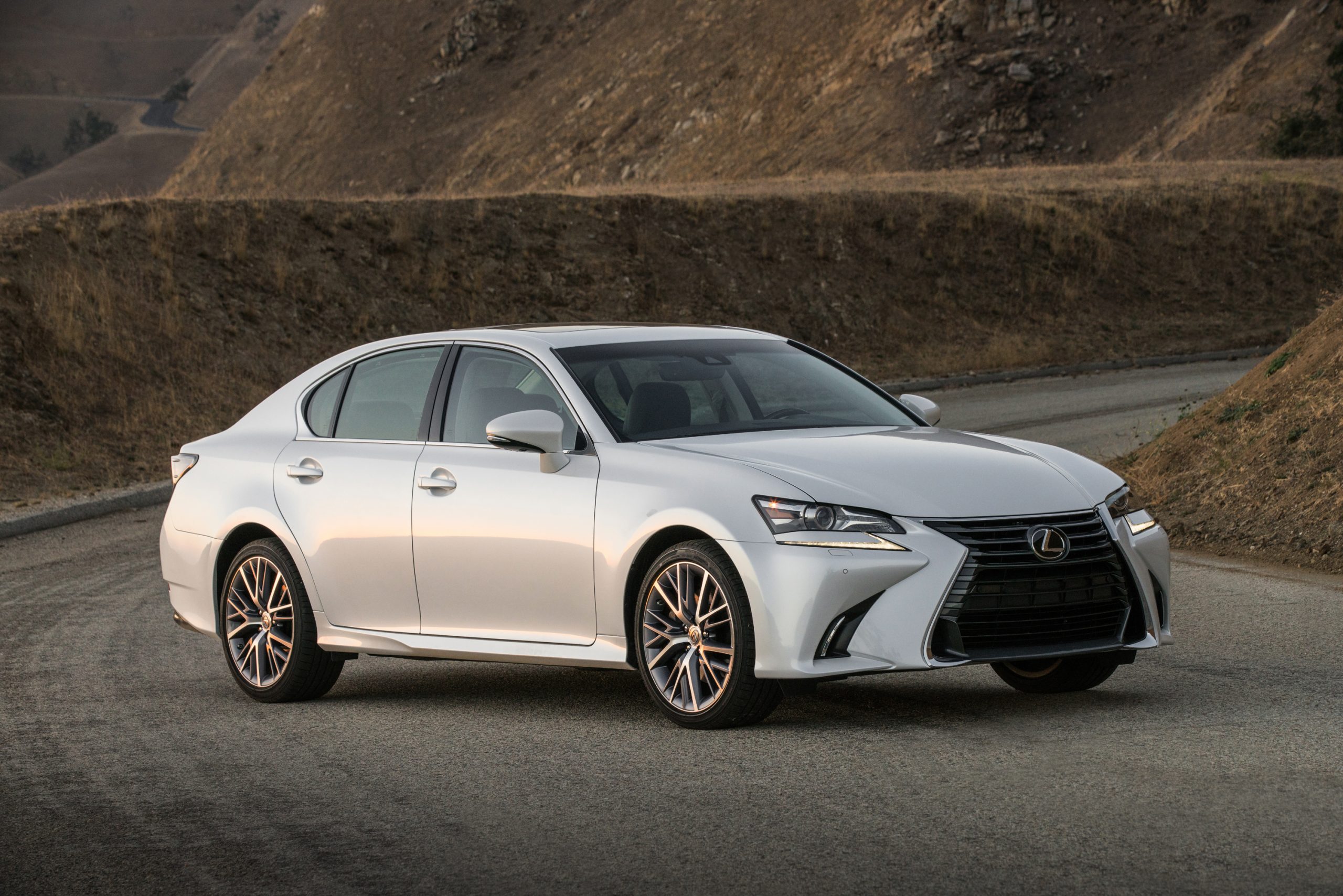 A white Lexus GS luxury car shot from the front 3/4 at sunset